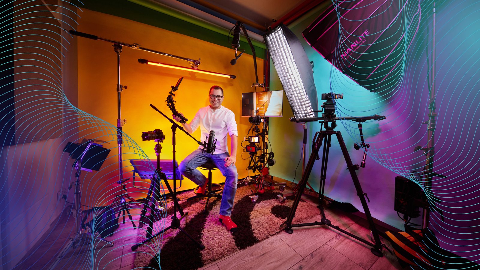Bartek Dziedzic w swoim studiu: kamera na statywie, mikrofon na wysięgniku, lampa z softboxem i kolorowe tło